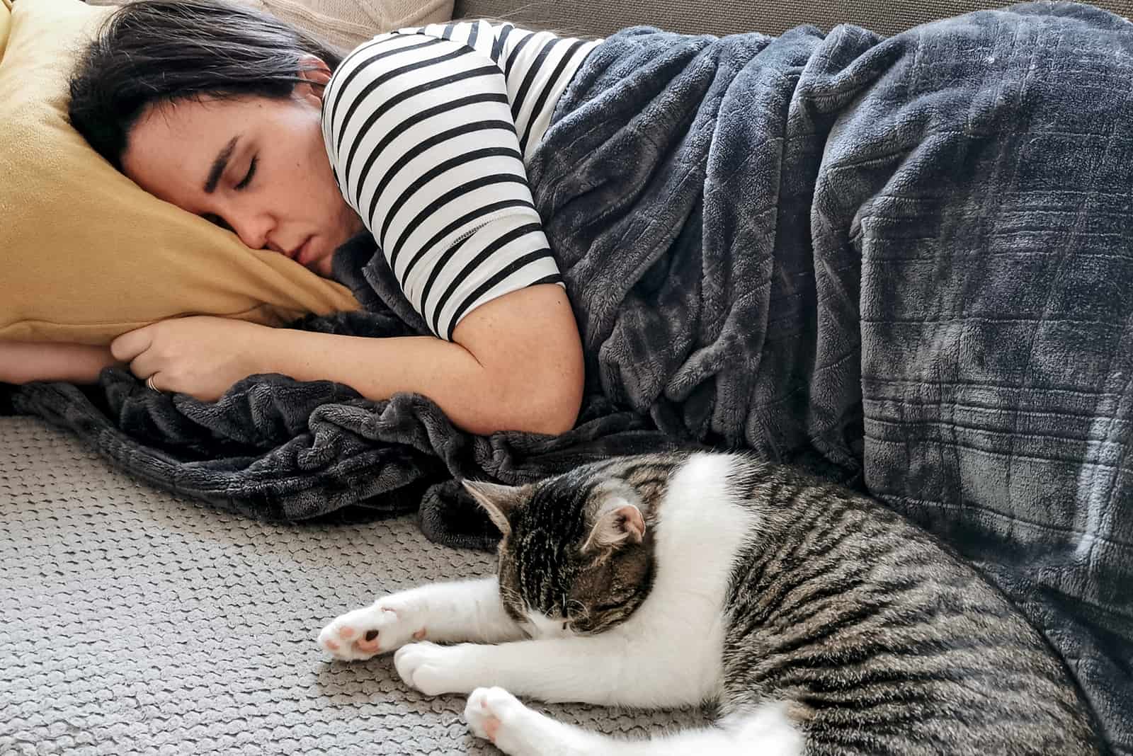a beautiful woman sleeps together with a cat on the bed