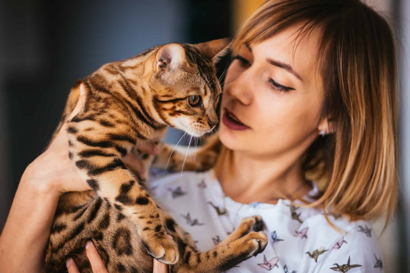 a woman holding a Bengal cat in her hand