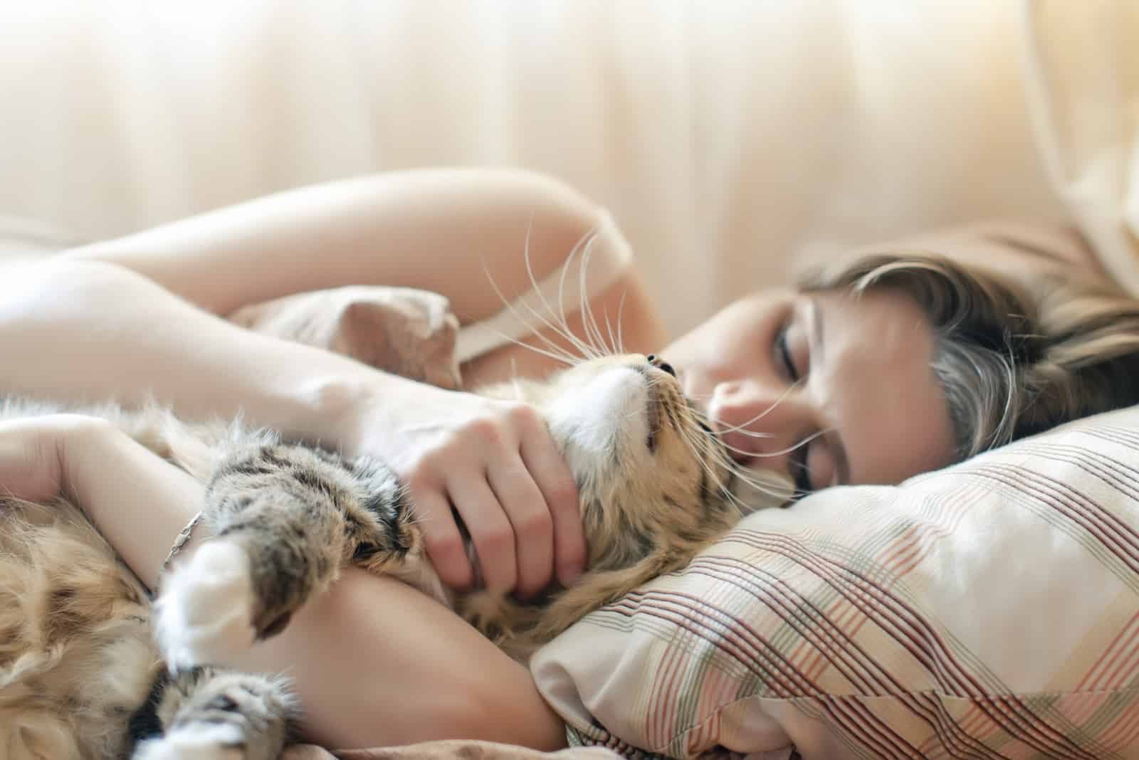 girl sleeping in bed with her cat