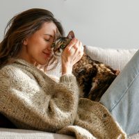 young woman cuddling with her cat on the couch