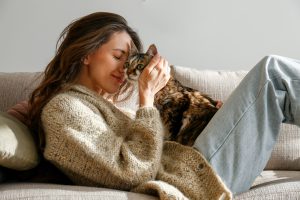 young woman cuddling with her cat on the couch