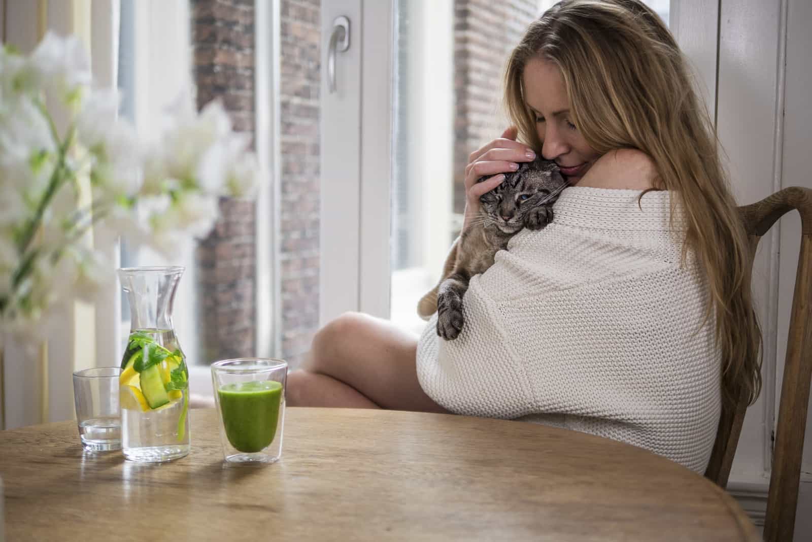 Pretty blonde cuddling her cat in the morning