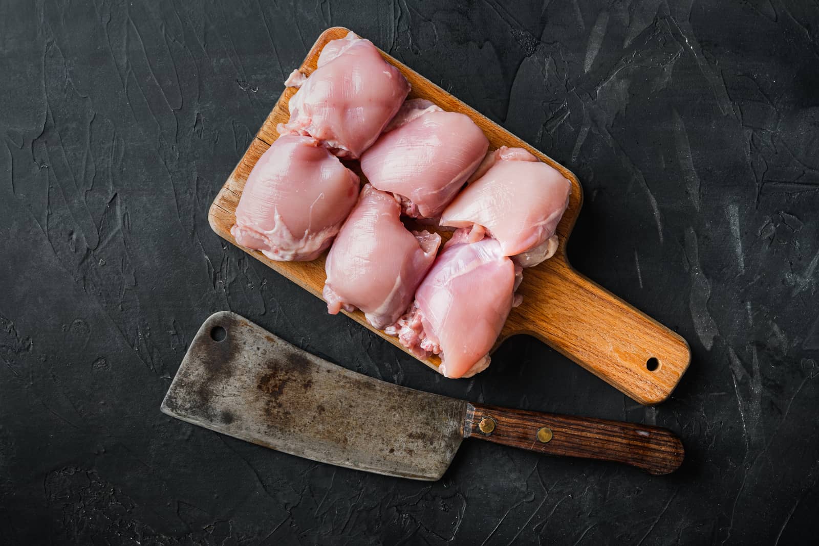 Raw chicken thighs with meat cleaver