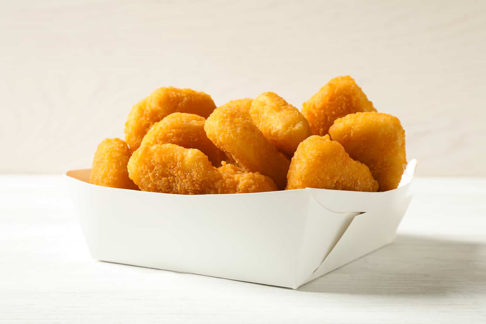 Tasty fried chicken nuggets on white wooden table