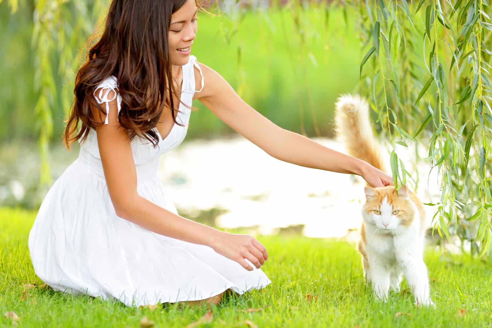 a woman playing with a cat in the garden