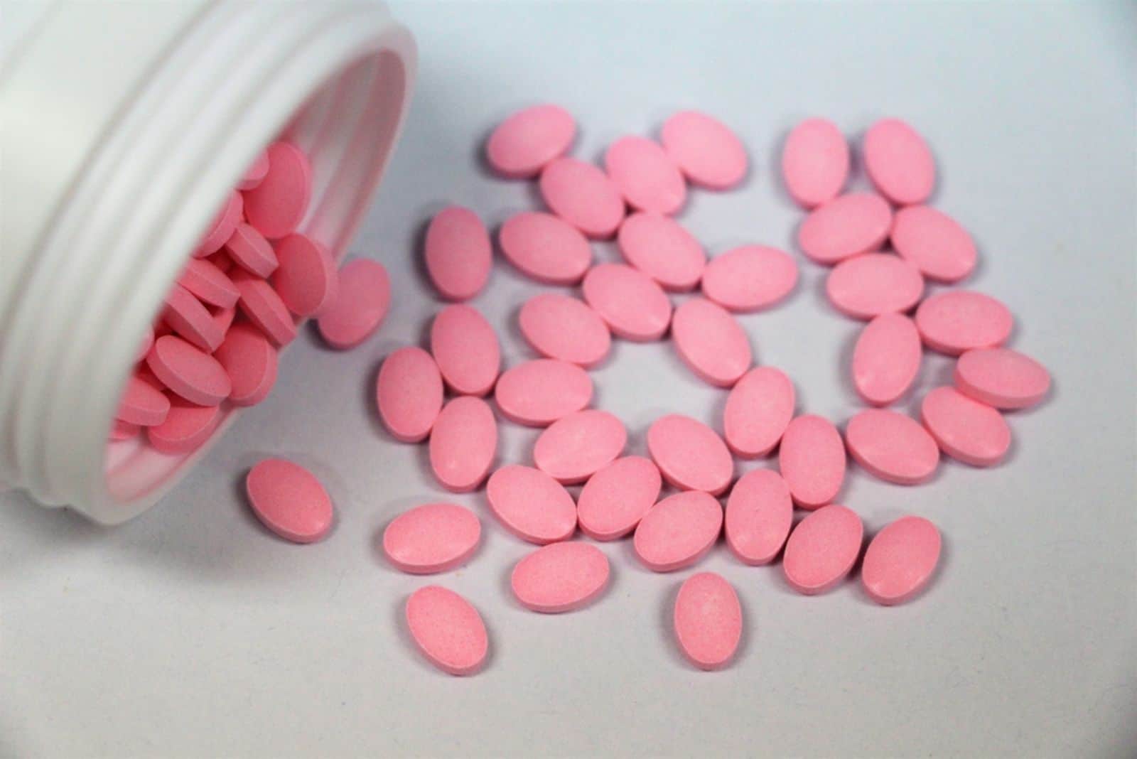 Top view of pink tablets on white background