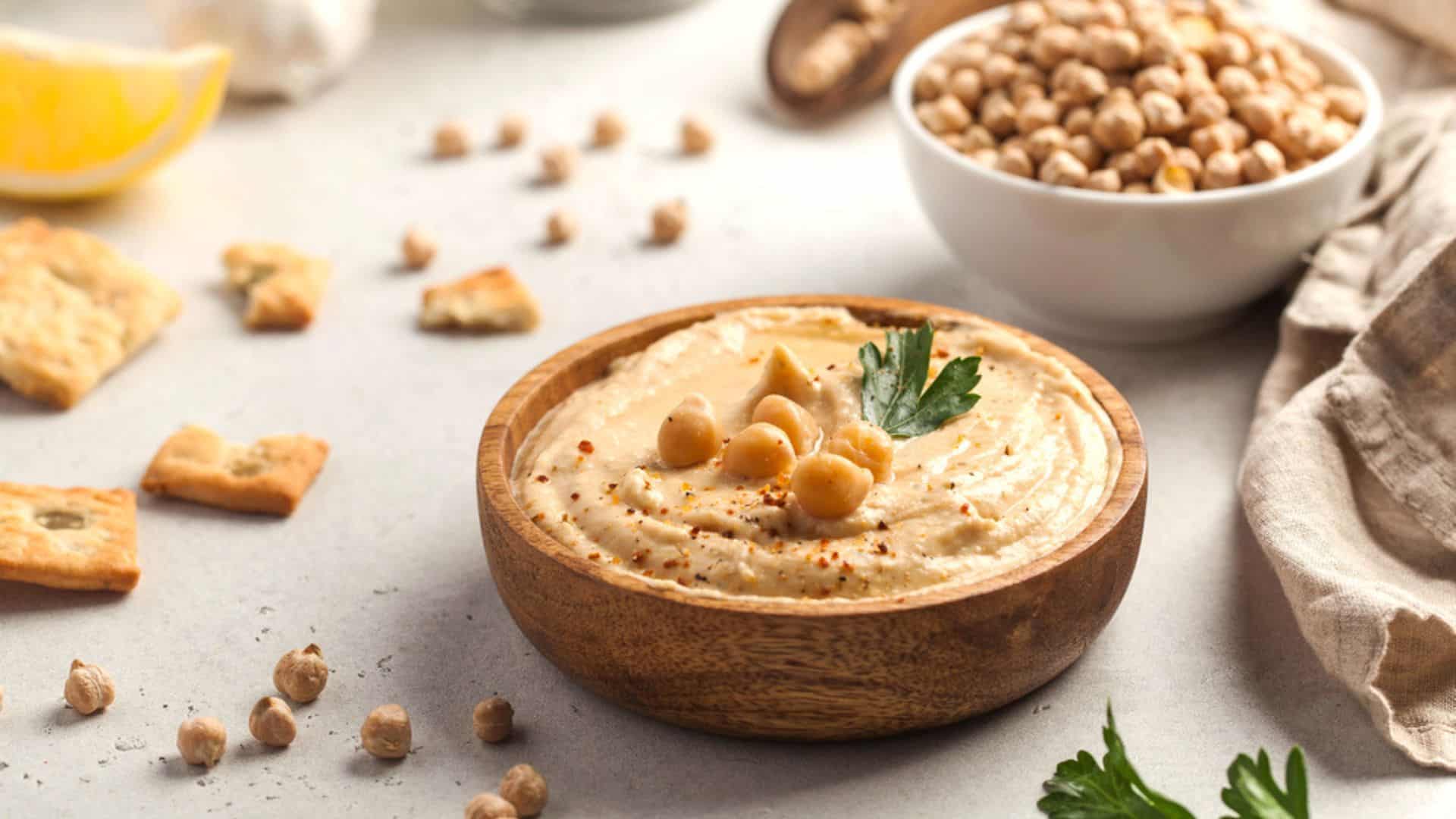Hummus in a wooden plate with parsley and croutons