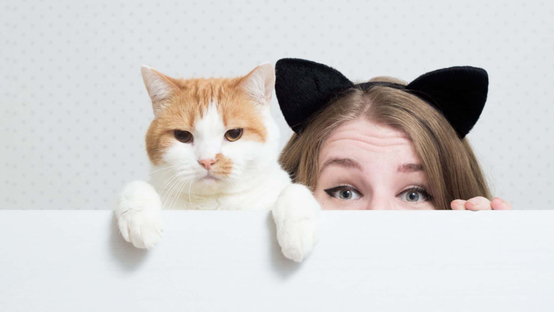 young woman with cat hiding behind a white banner