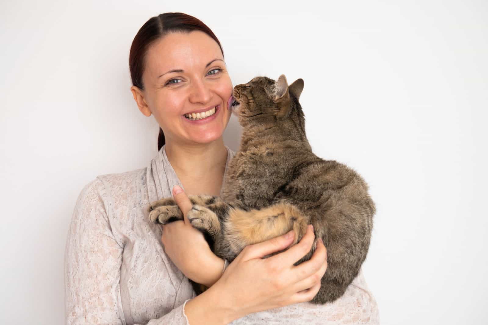 cat licks woman's cheek