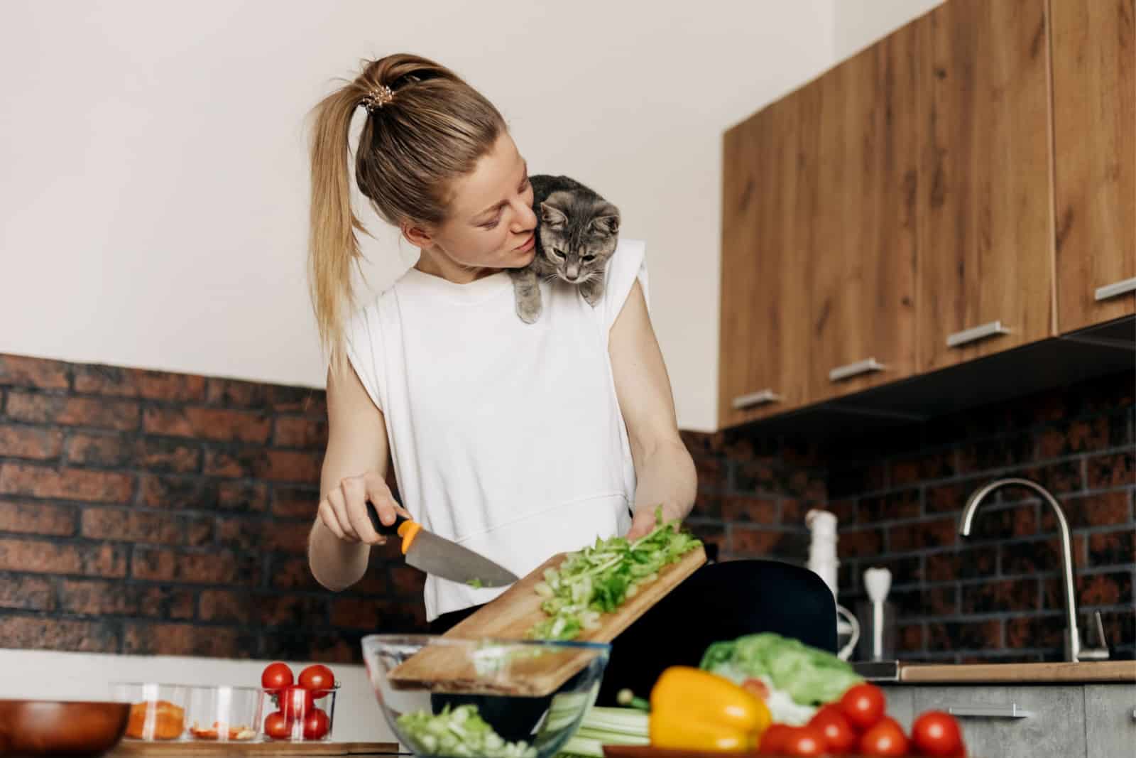woman cooks in kitchen with cat