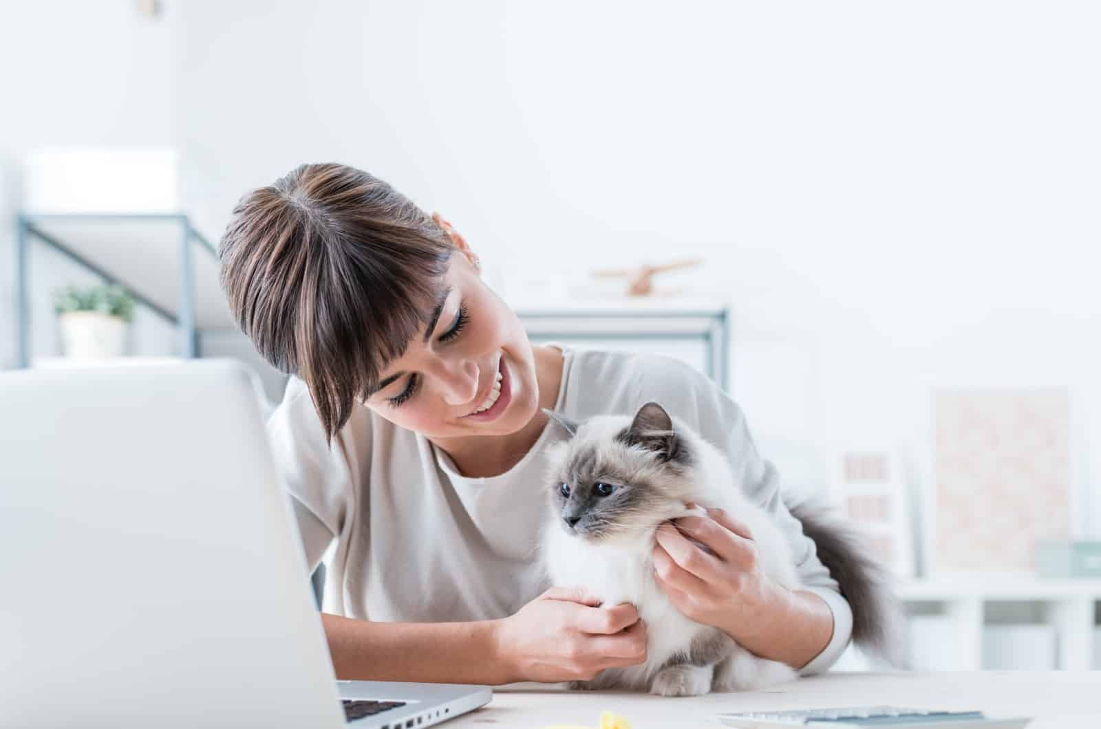 woman petting her cat while working