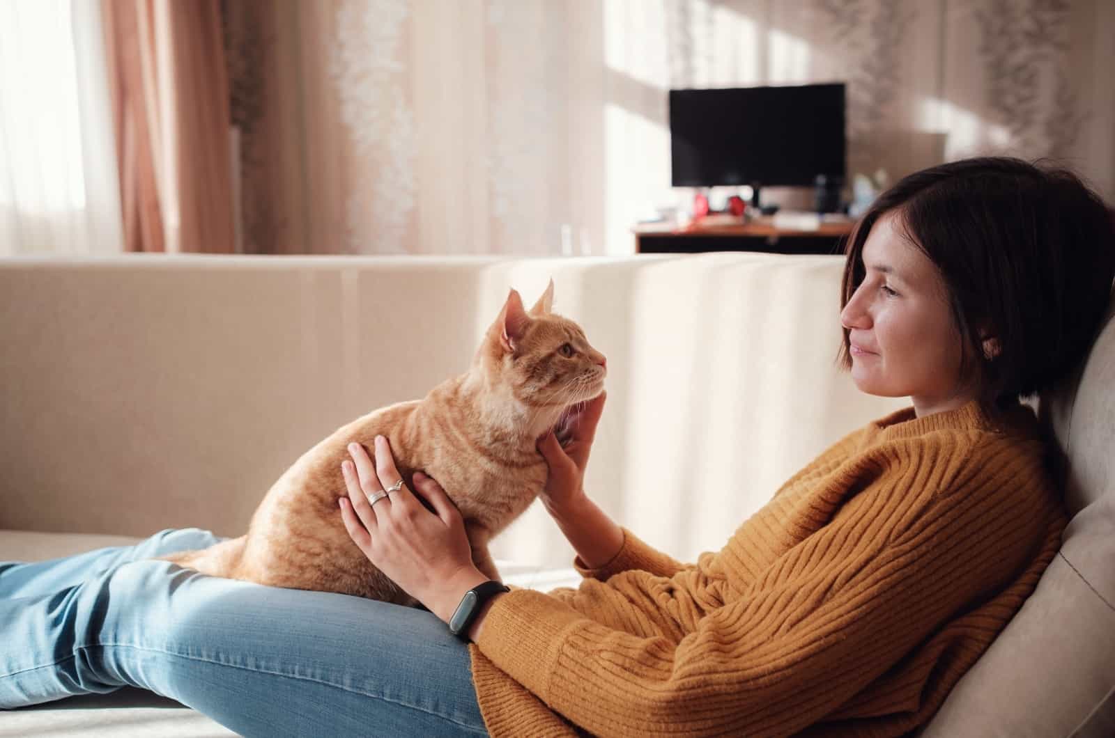 woman playing with her orange cat