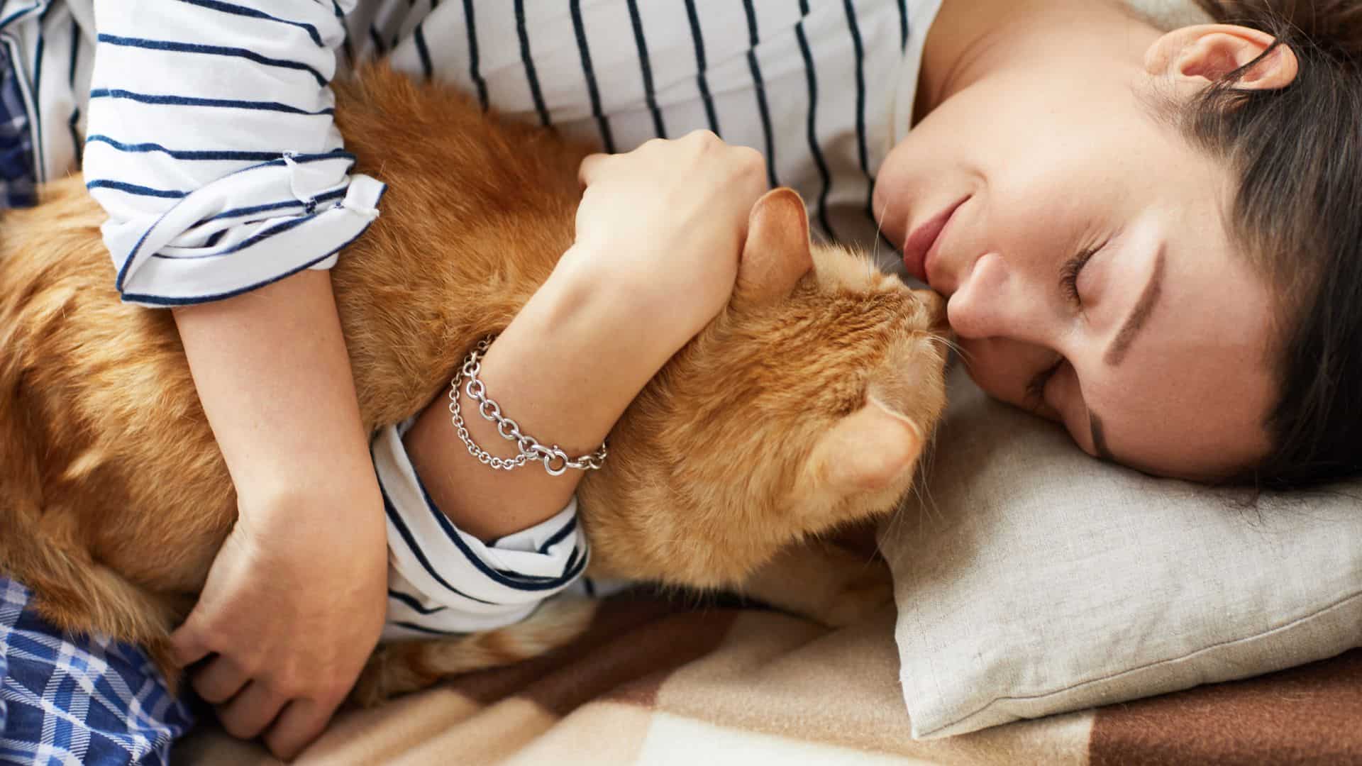 a woman sleeps with a cat in her arms