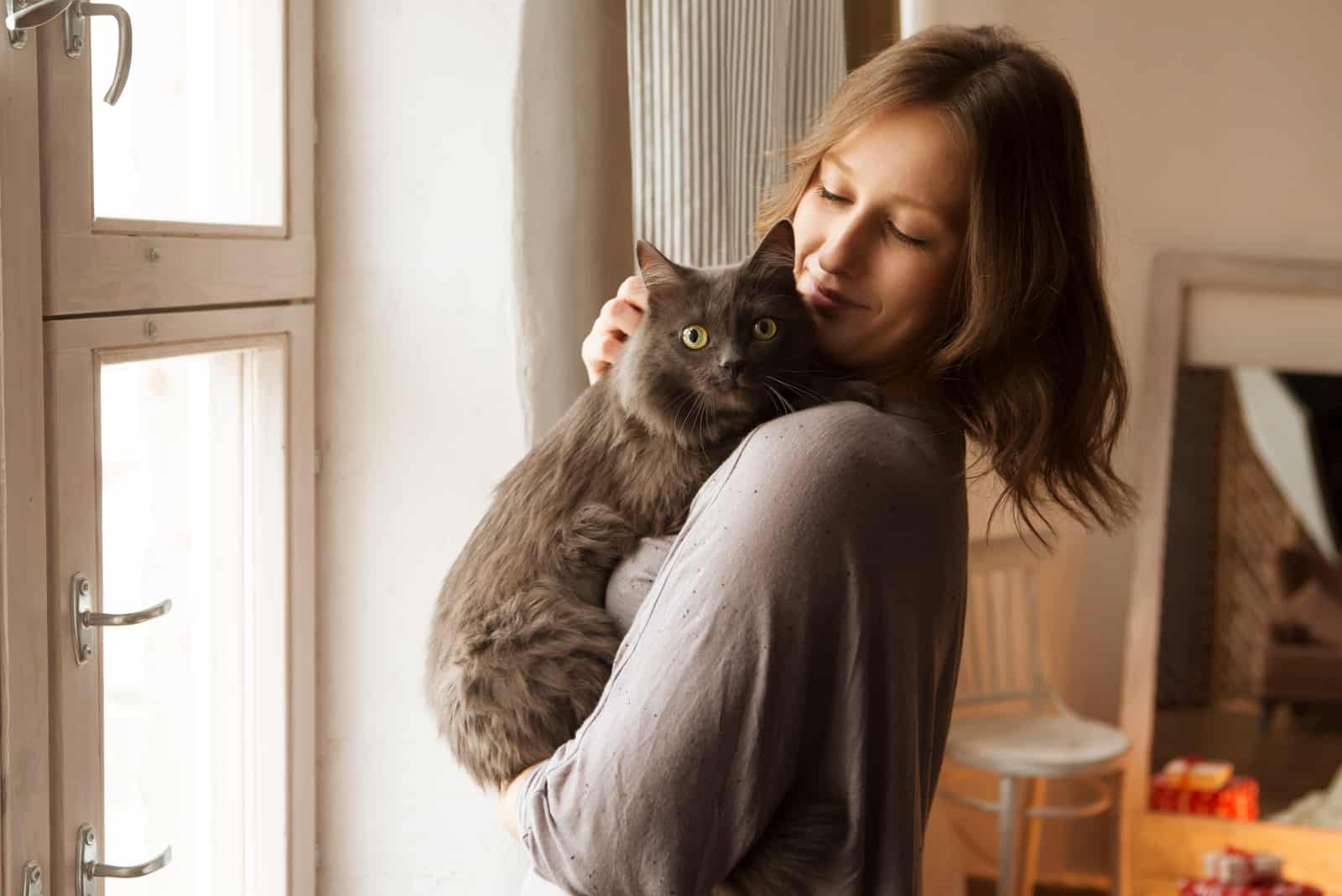 Young woman playing with cat in home