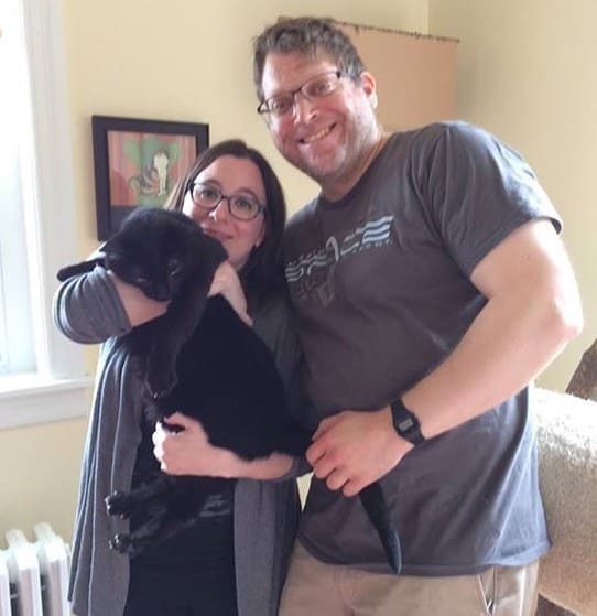 man and woman posing with their adopted cat