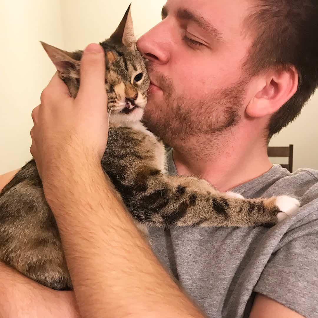 a man hugs a one-eyed cat