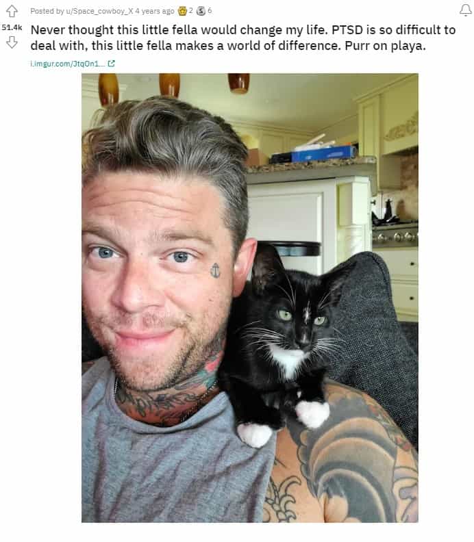 a man takes a picture with a cat sitting on his shoulder