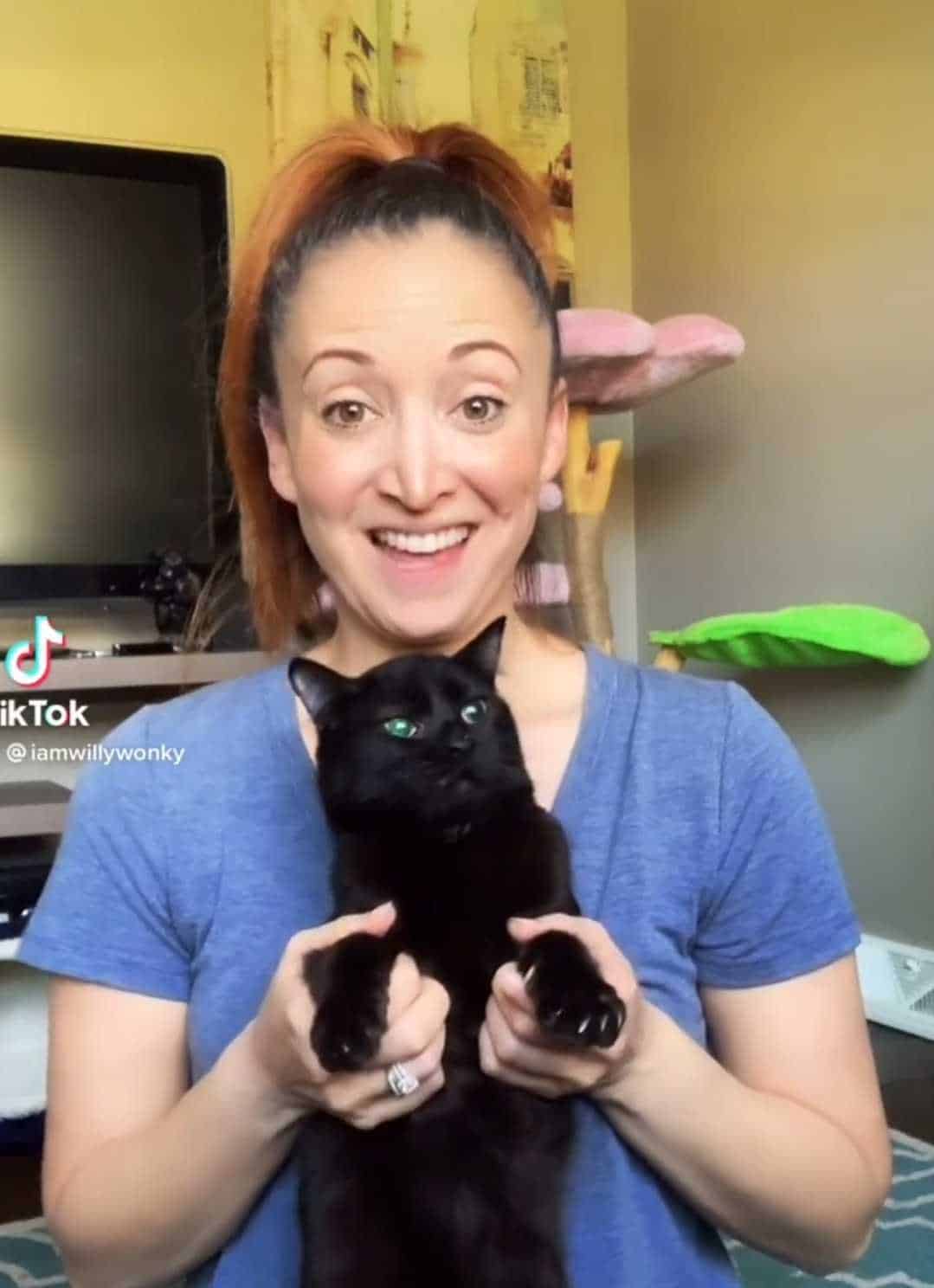 the woman is holding a black kitten