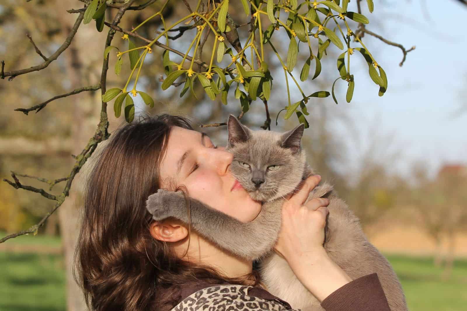 a girl kisses a gray cat