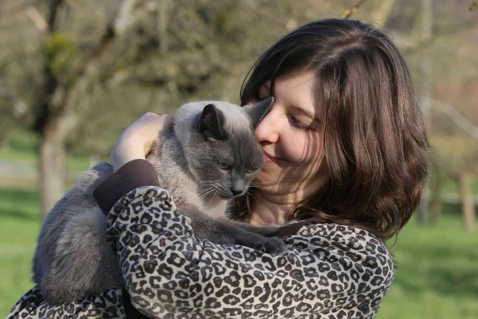 a smiling girl holds a cat in her arms