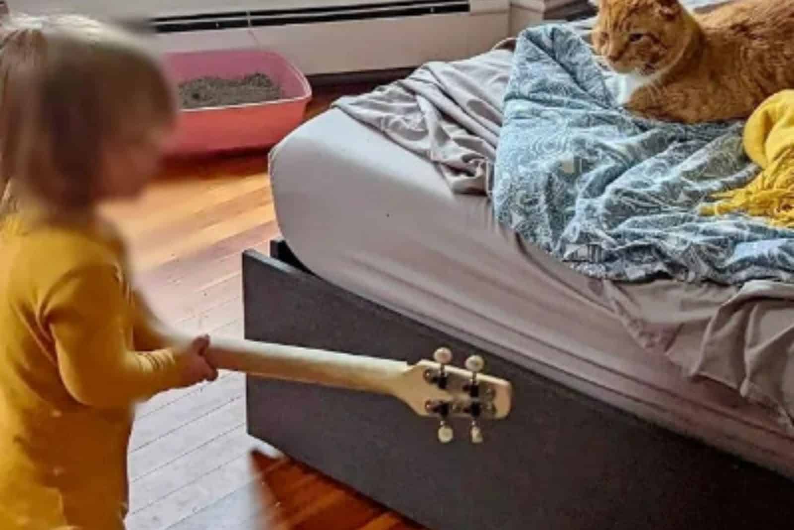 the child entertains the cat while lying on the bed