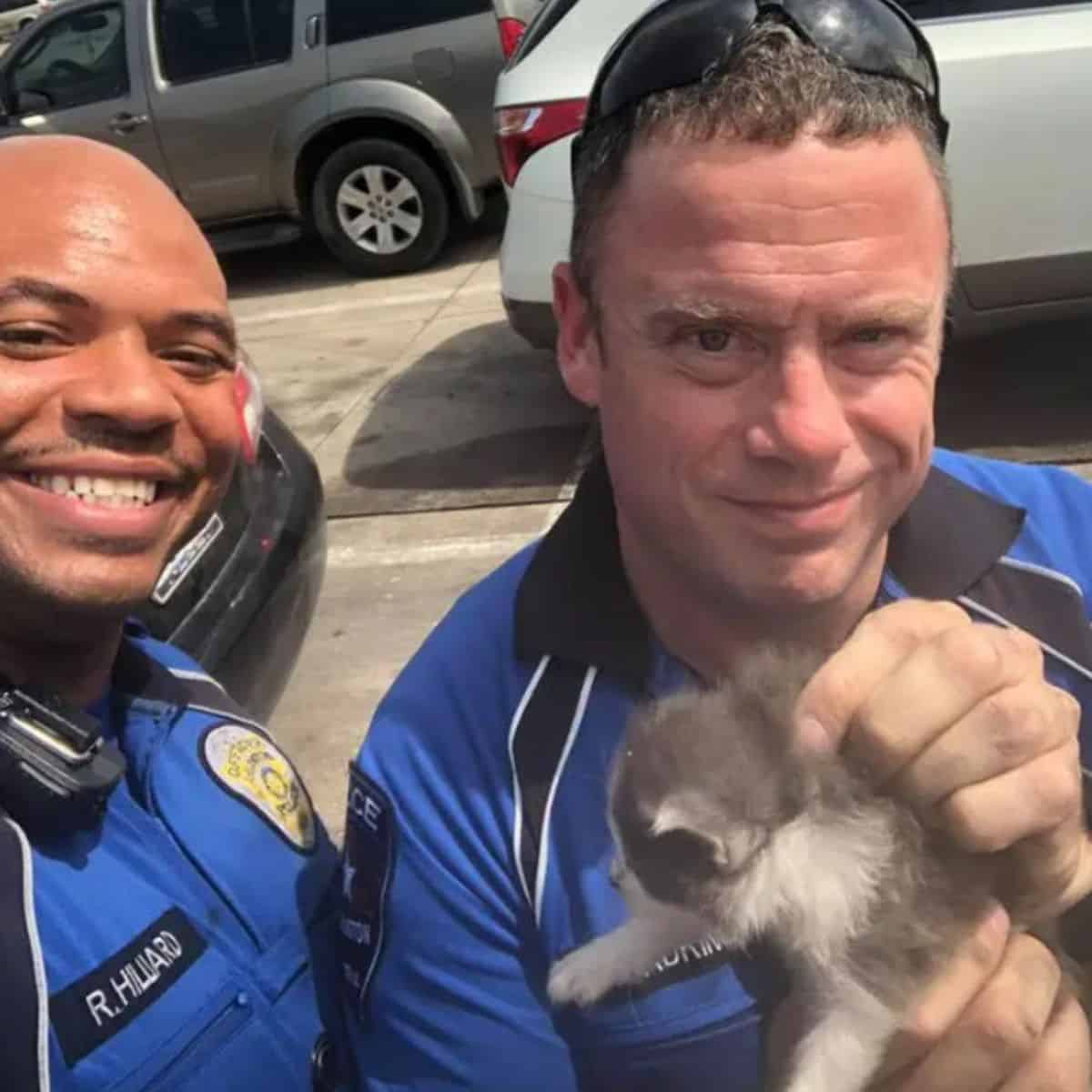 two police officers take a picture with a cute cat
