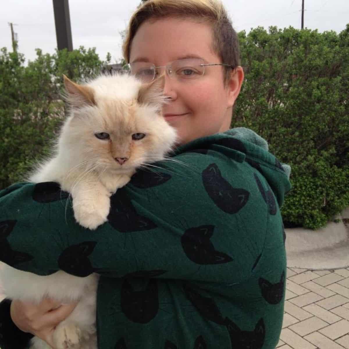 a woman holds a white adopted cat in her arms