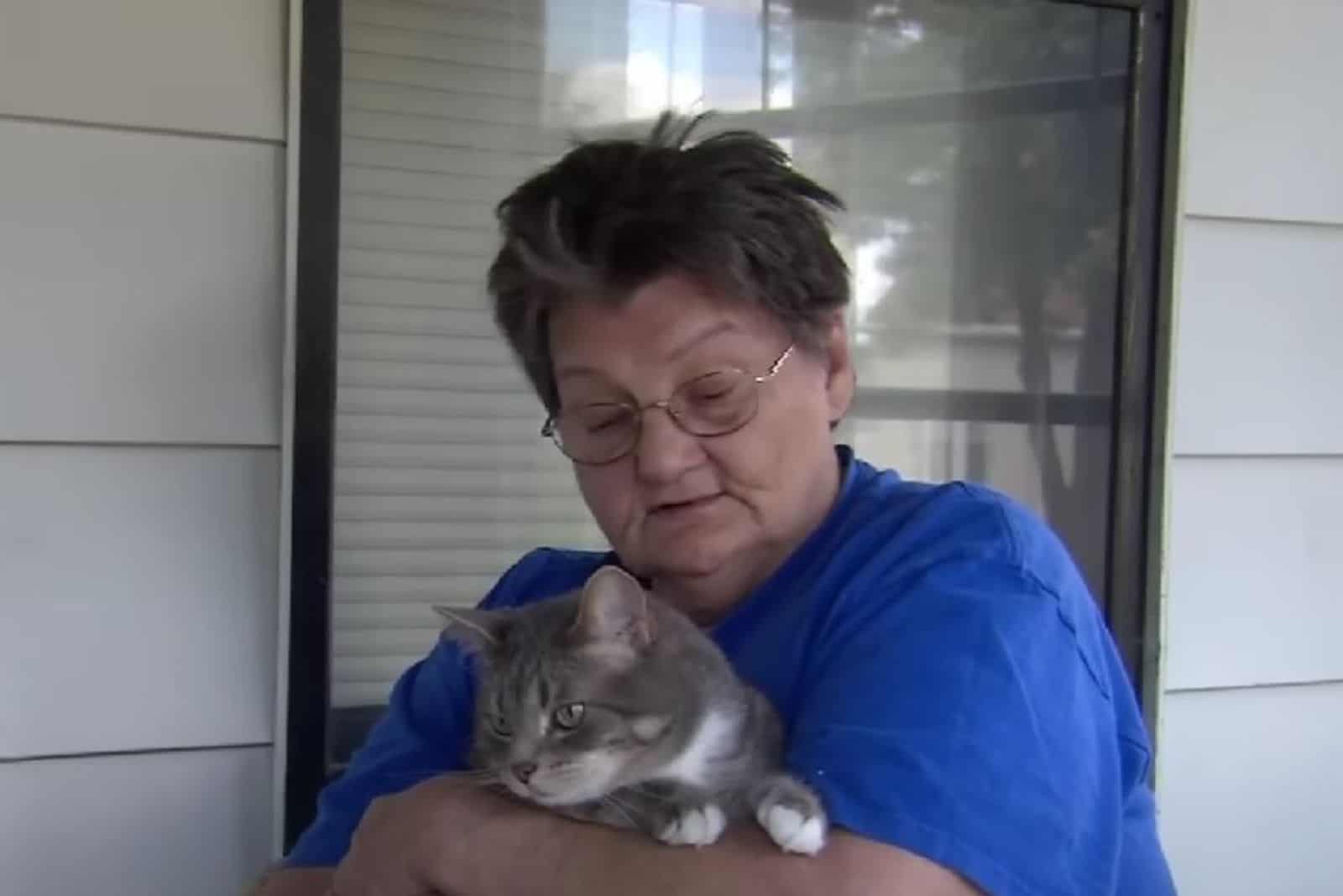 a woman with glasses holds a cat in her arms
