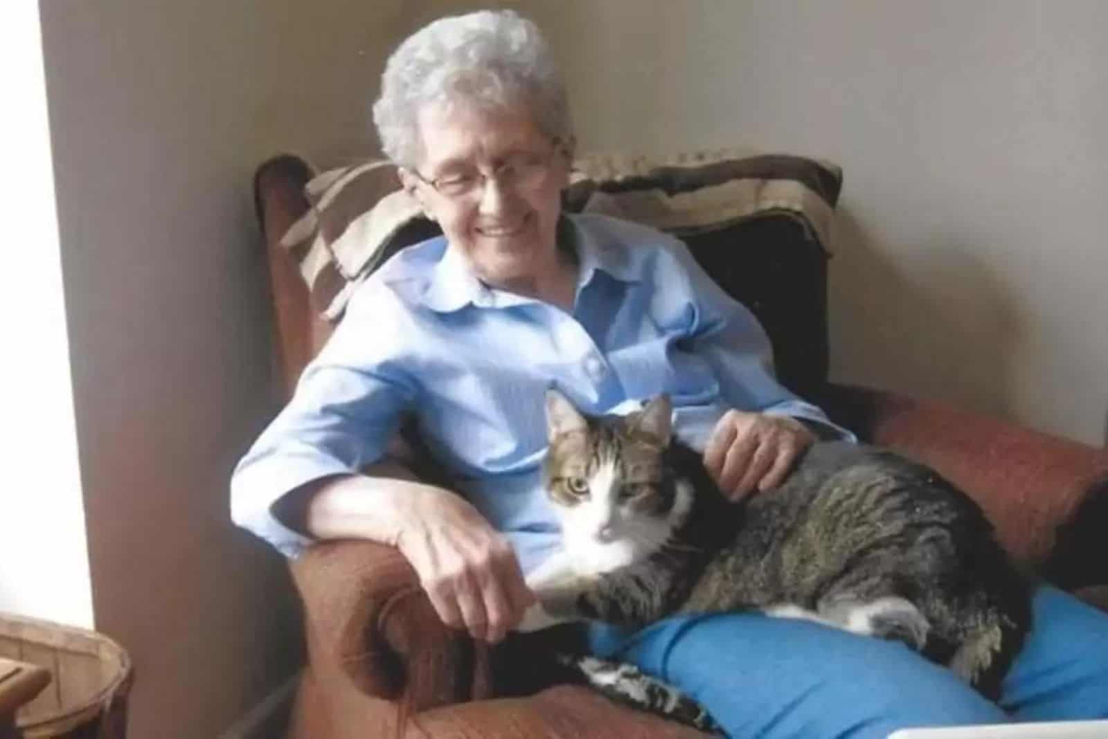 older woman smiling while sitting in a chair with a cat in her lap