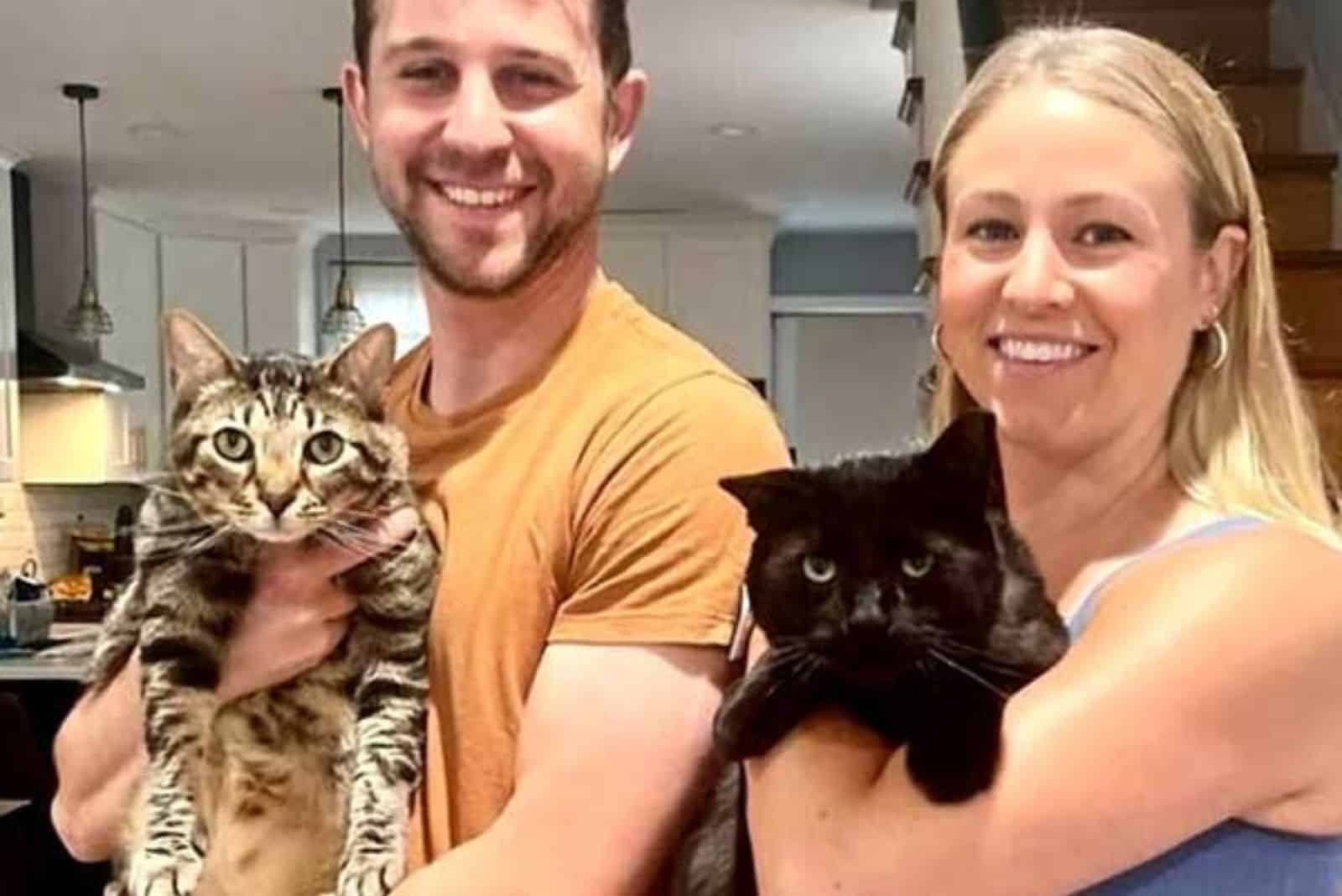 smiling loving couple holding their cats in their arms
