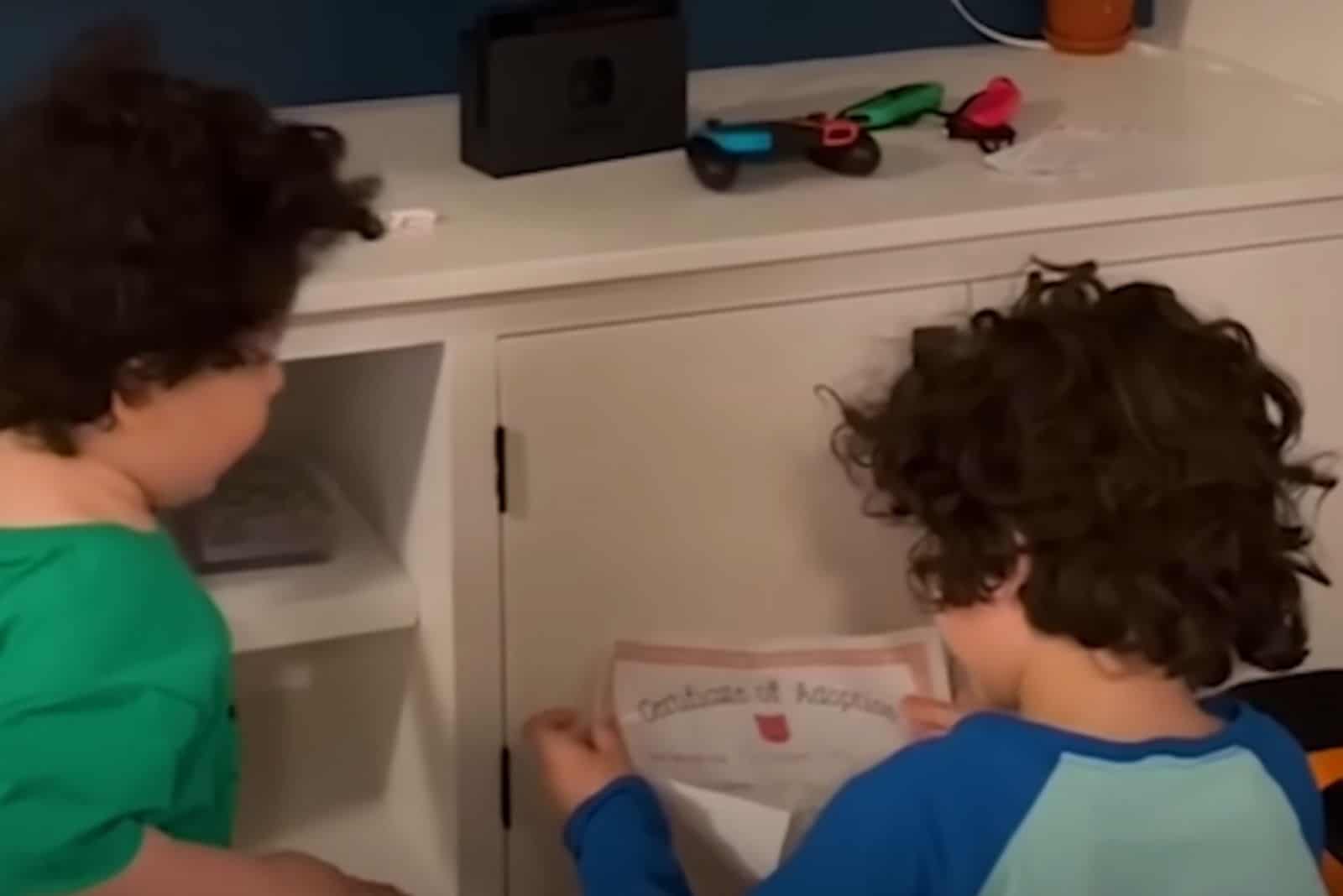 two boys are reading from a paper