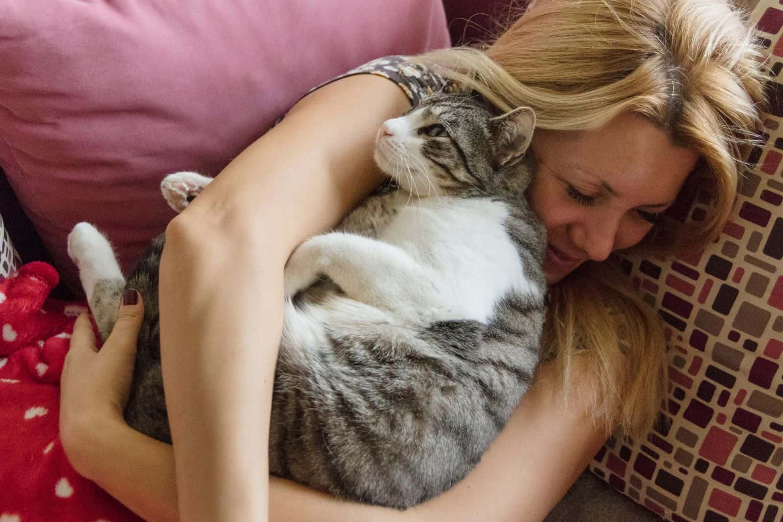 woman and a cat cuddling while lying on the couch