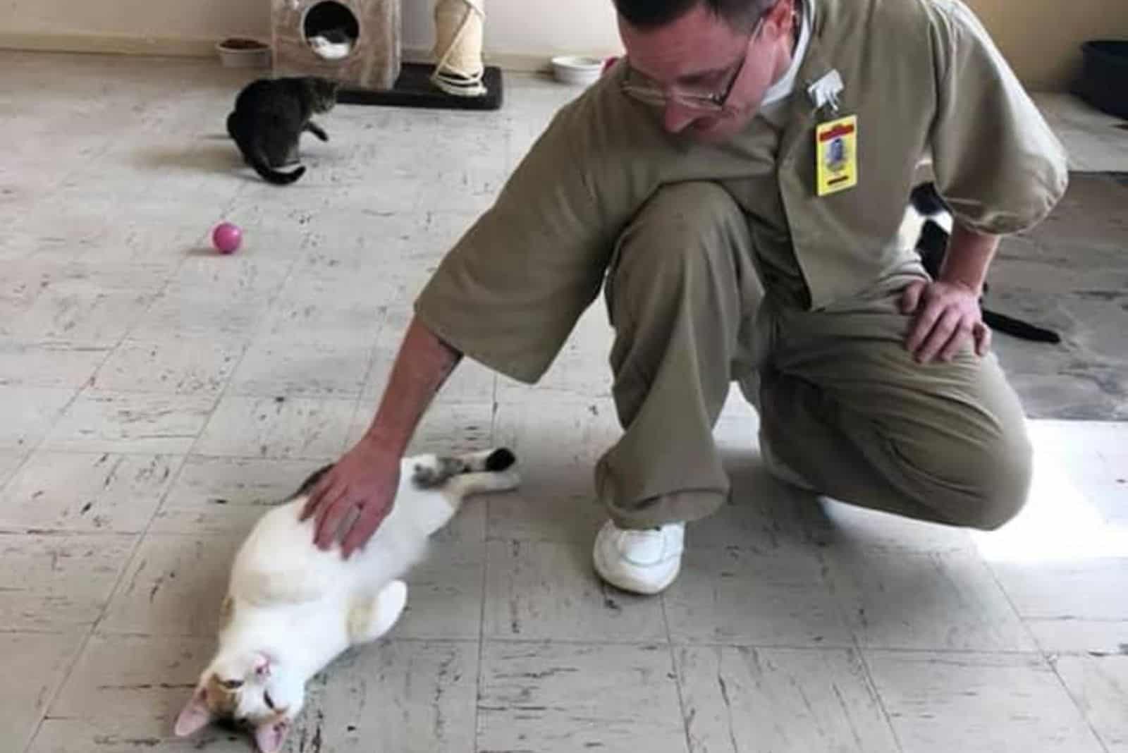 Guy petting cat on the floor