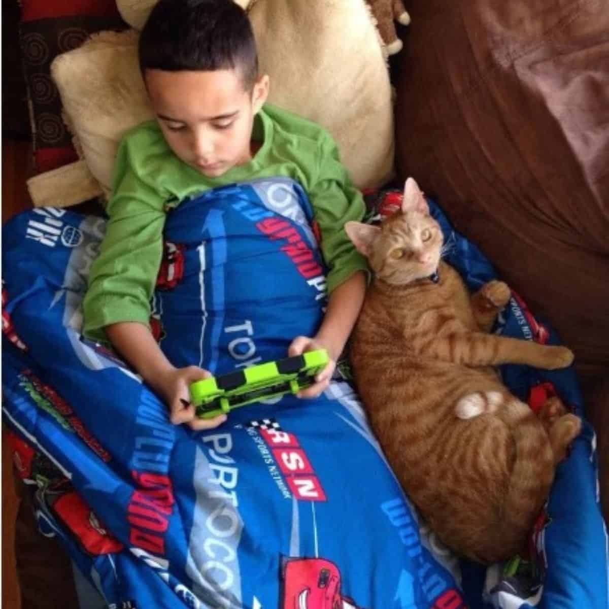 boy playing games with cat next to him