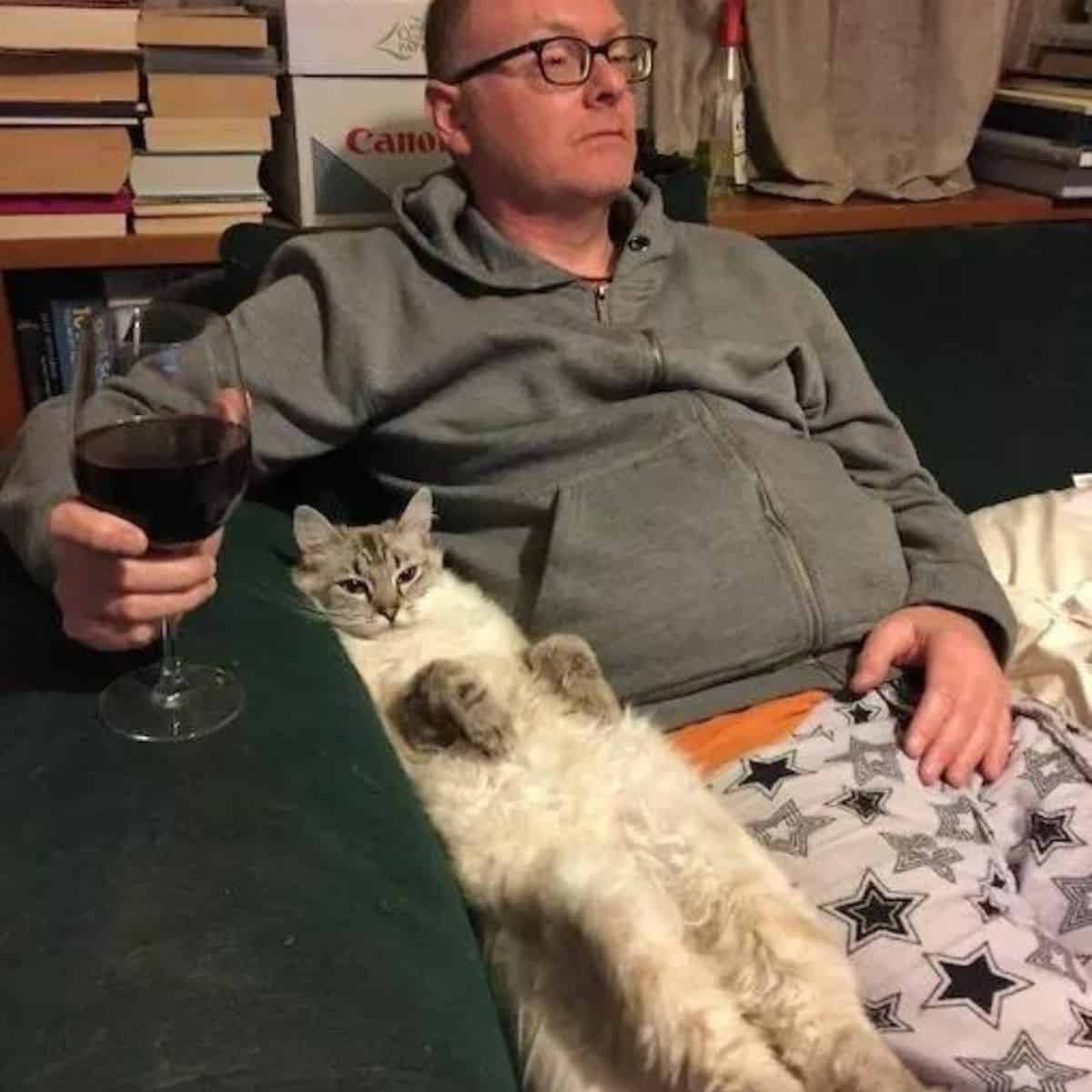 man relaxing with cat and glass of wine