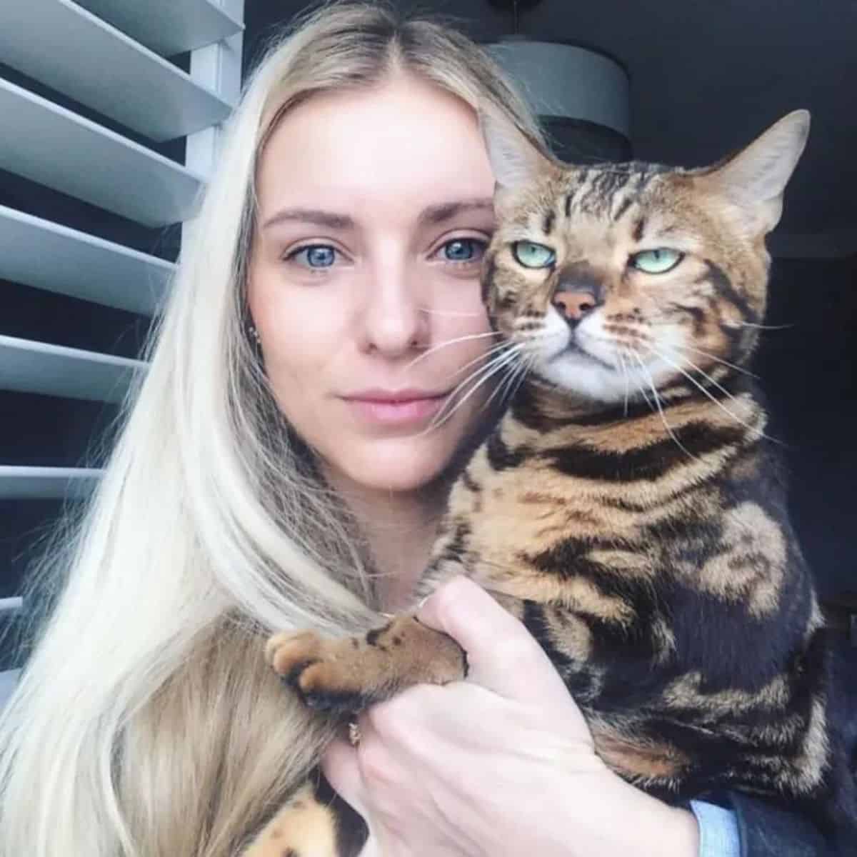 a girl takes a picture with a tiger cat