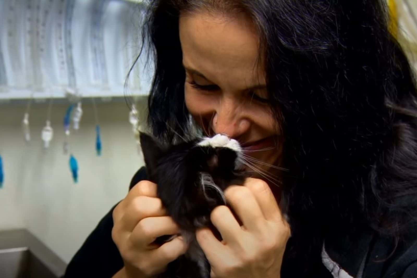 a smiling woman bothers a kitten
