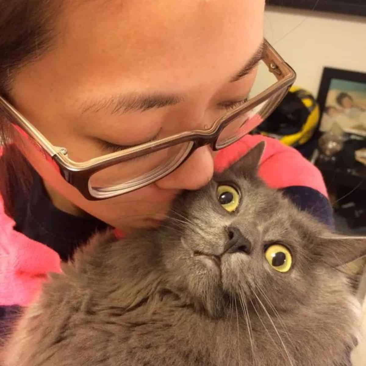 a woman with glasses kisses her cat