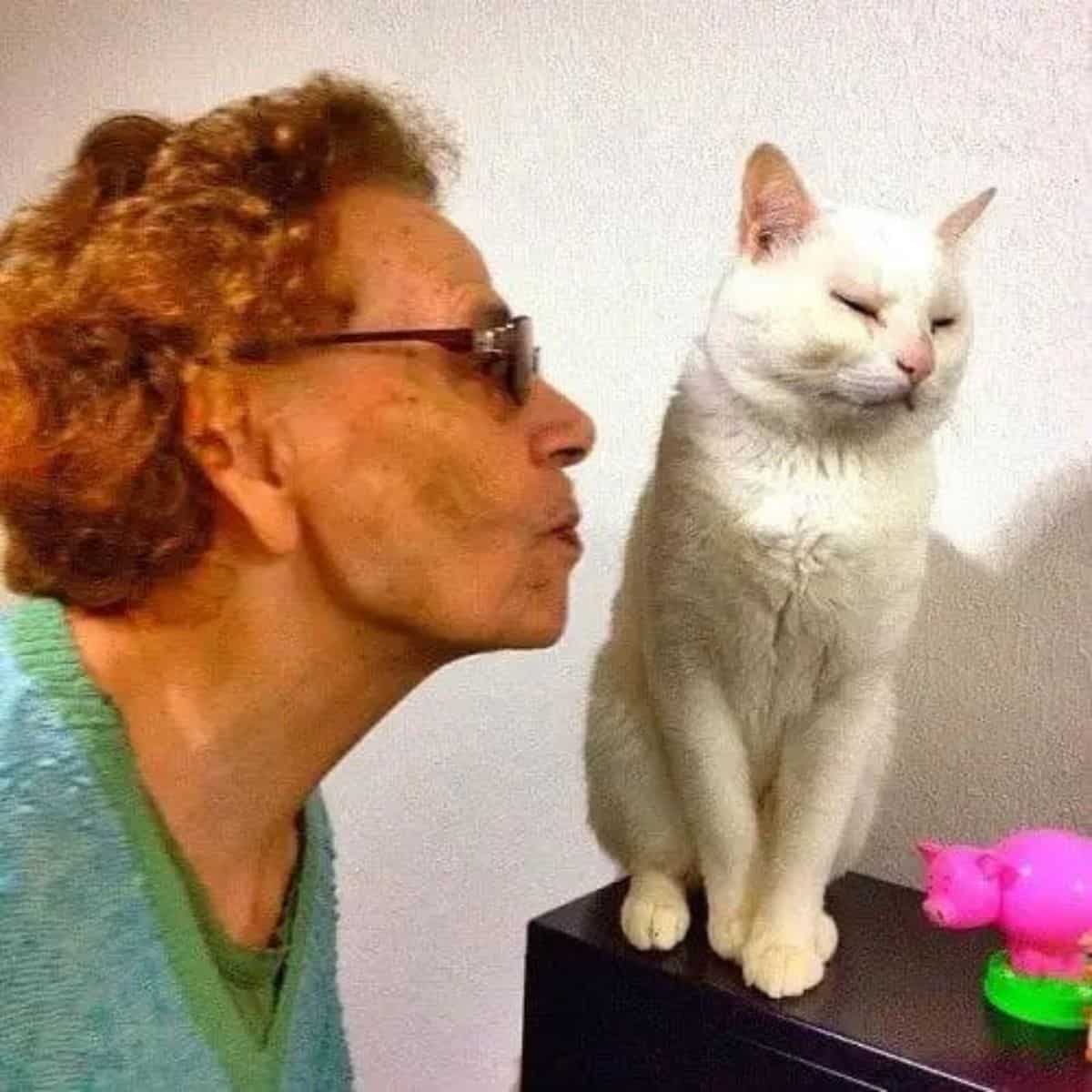 the grandmother approaches the cat to kiss it