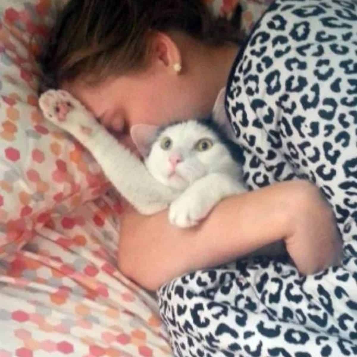 the woman hugged the cat while she was sleeping