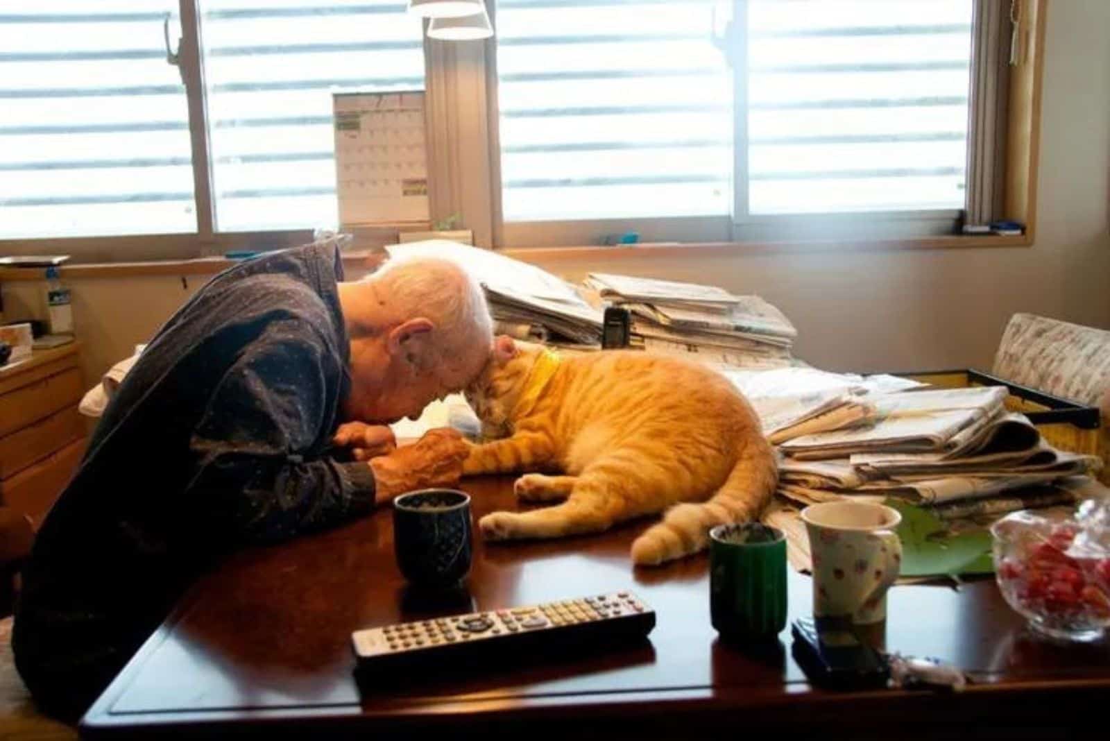 old man cuddling with cat on the table