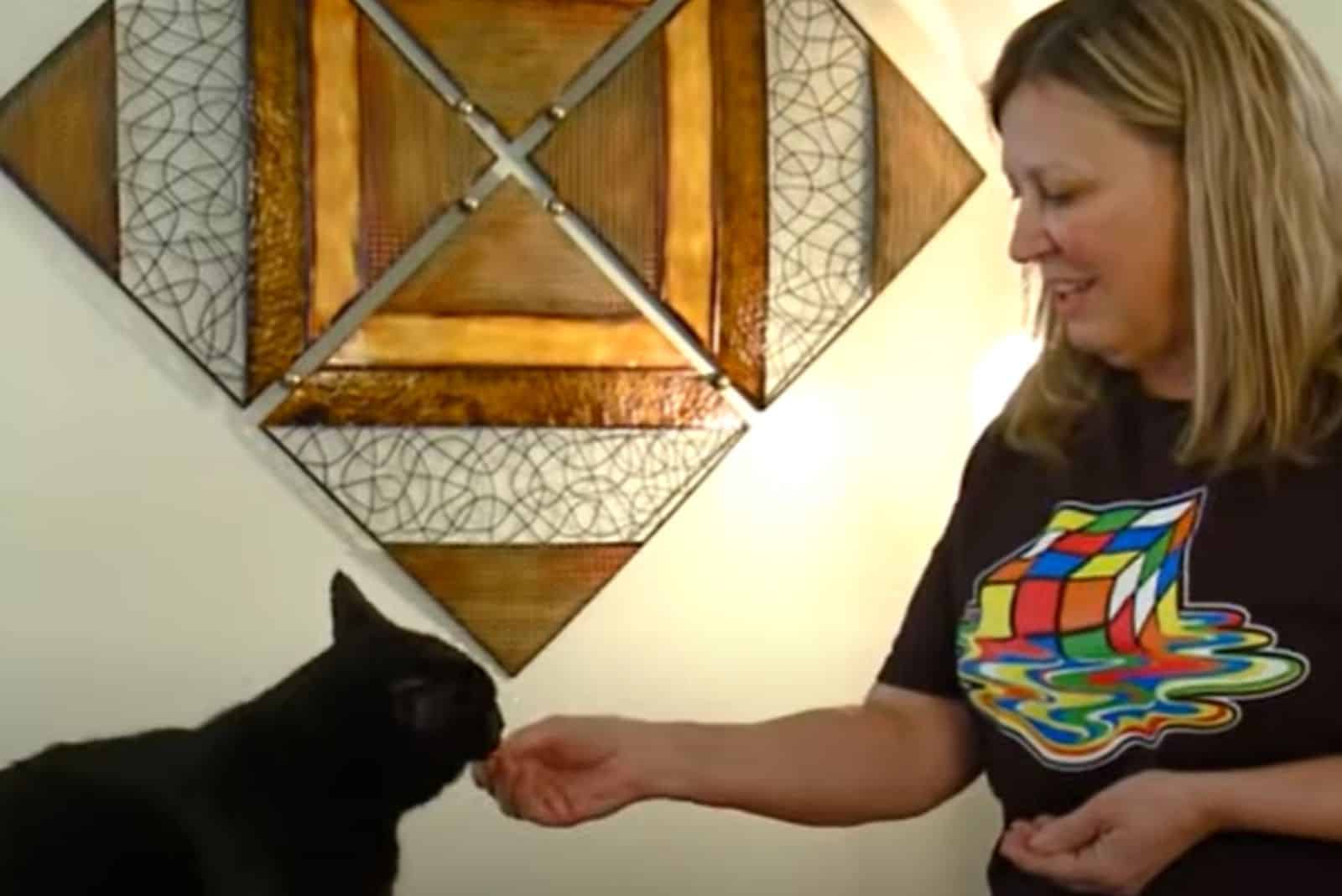 woman feeding black cat