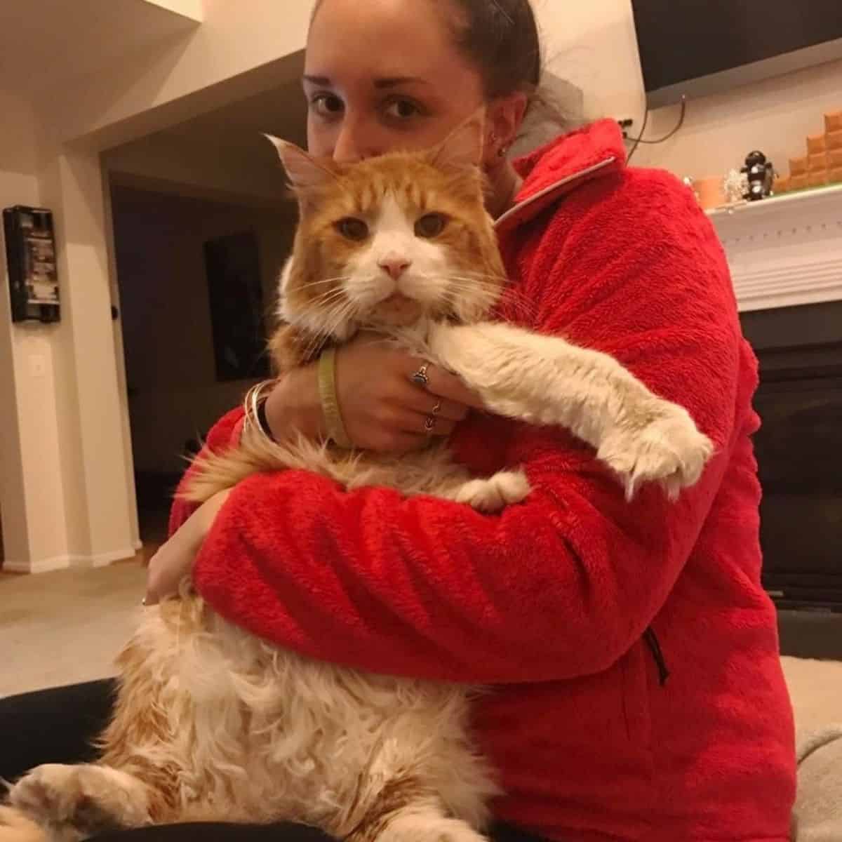 woman in red hoodie holding giant cat