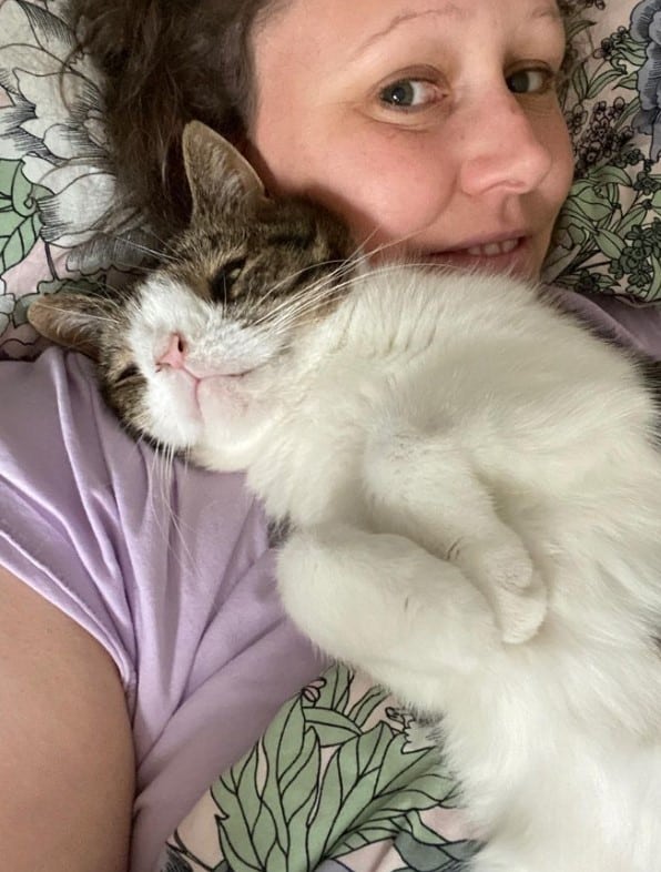 a cat with special needs lies in the arms of a woman