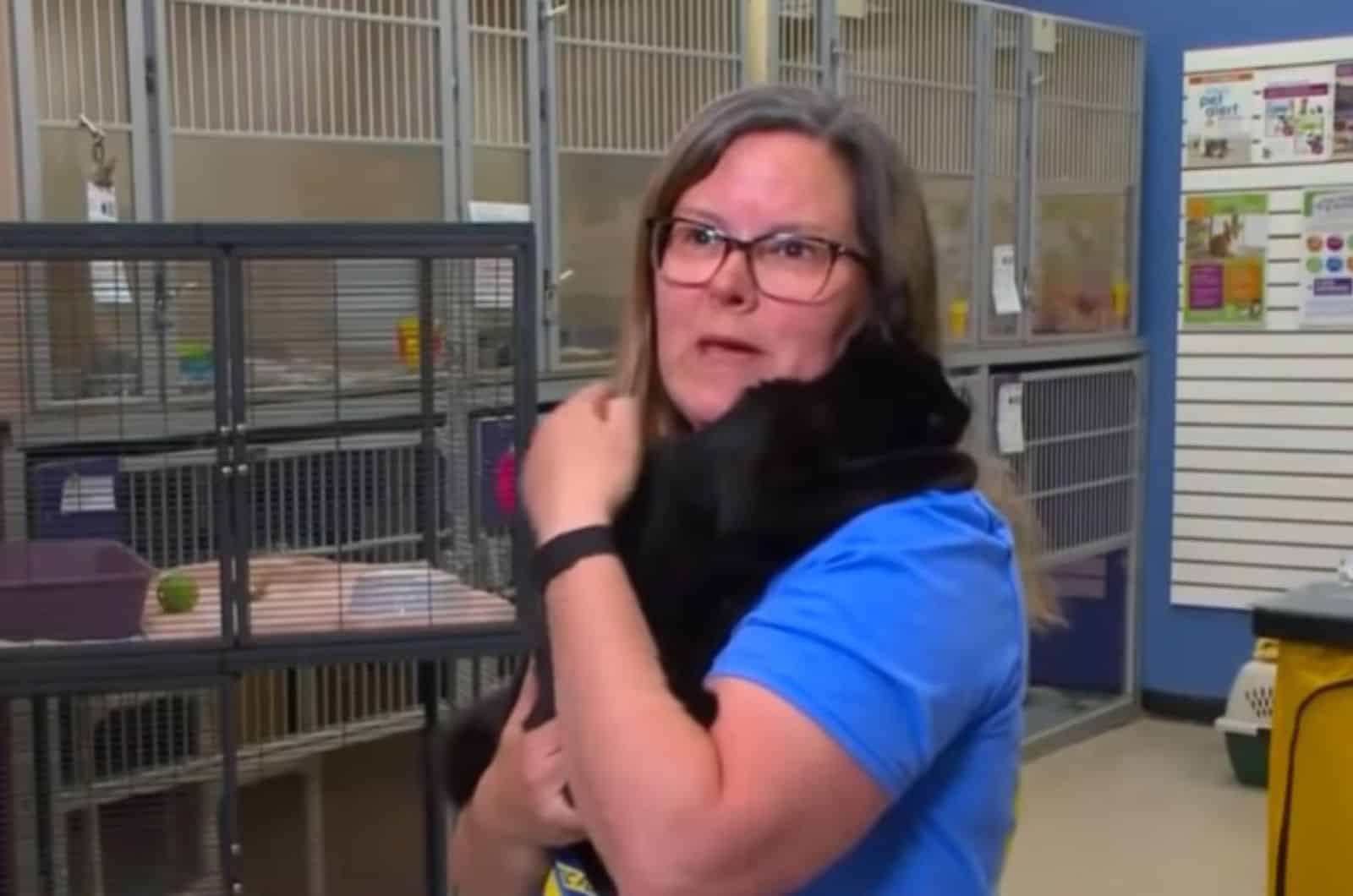 the veterinarian holds a black cat in her arms