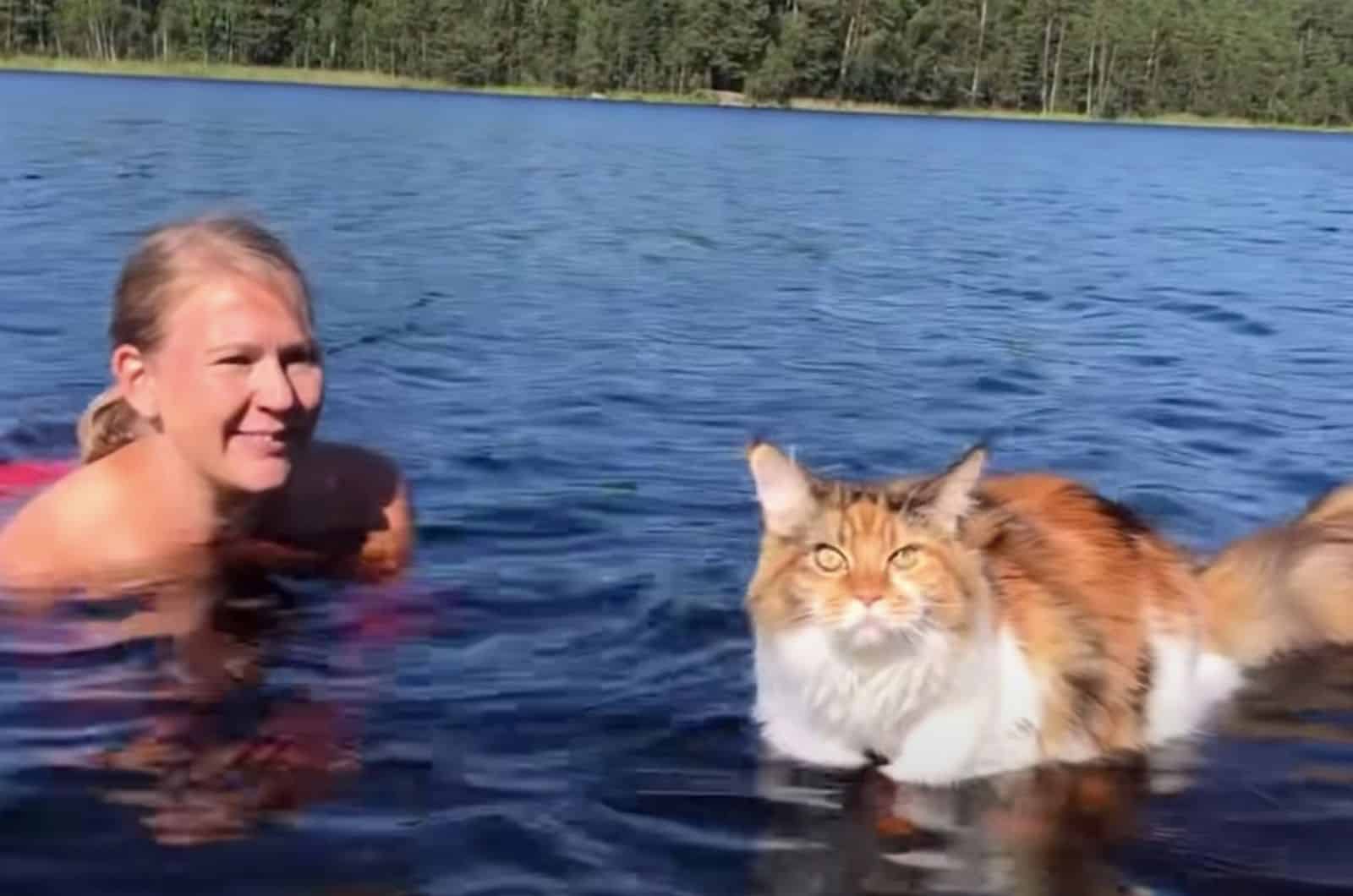 photo of maine coon cat and owner in water