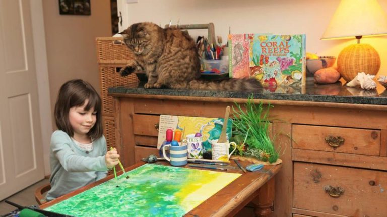 girl with autism painting and a cat sitting by her side