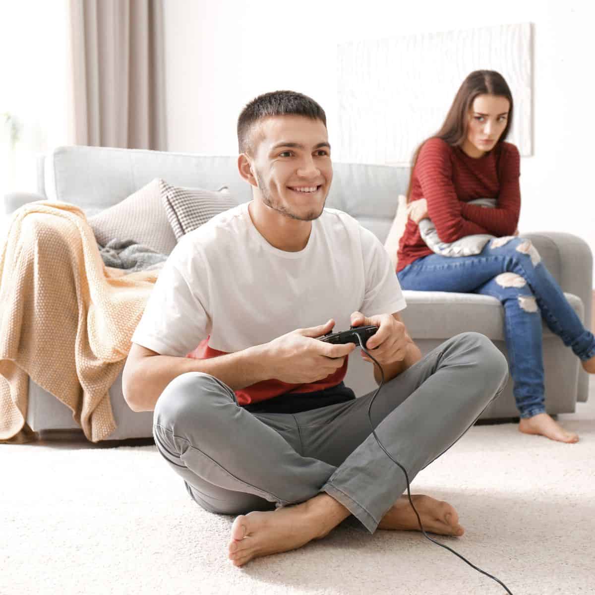 angry woman looking at man playing a game