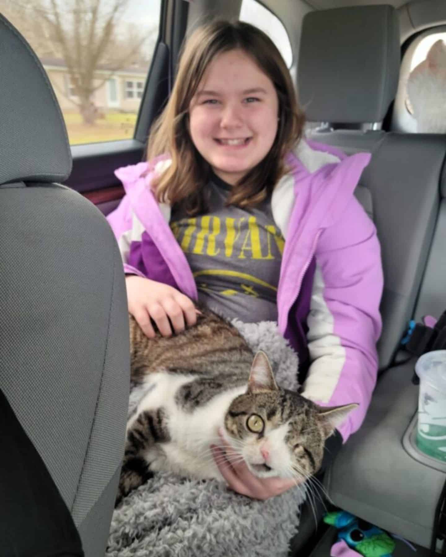 little girl sitting in car with cat in her lap