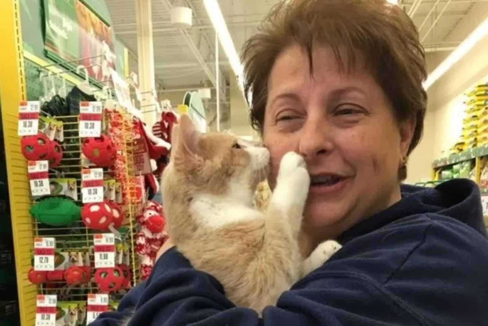 old woman hugging a cat in a store